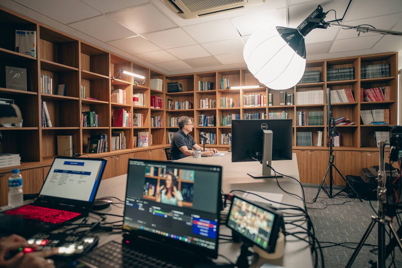 Set de videocast montado pela HR em biblioteca, com câmeras, iluminação e mesa de corte
